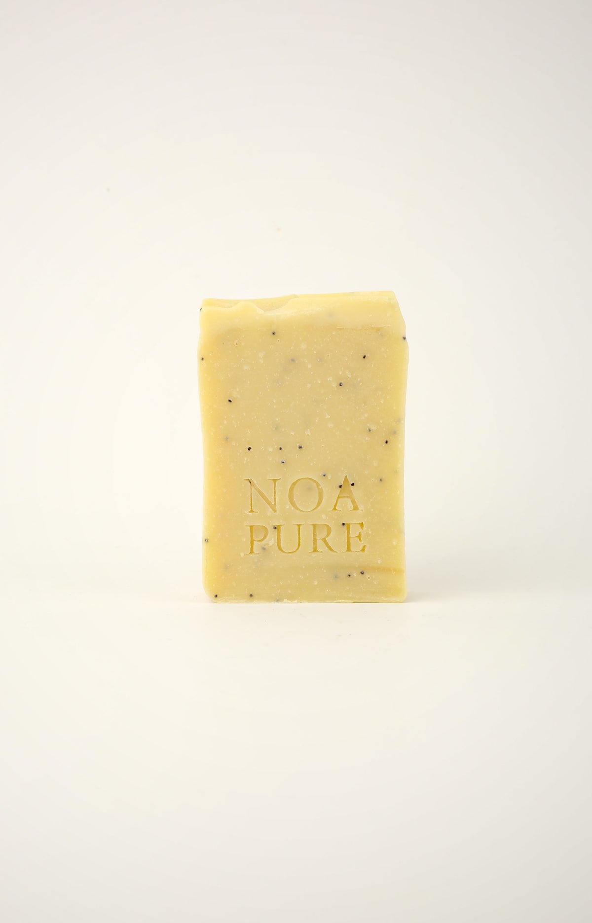 Exfoliating Body Ritual Bar with pale yellow botanical soap and NoaPure embossing on a white background