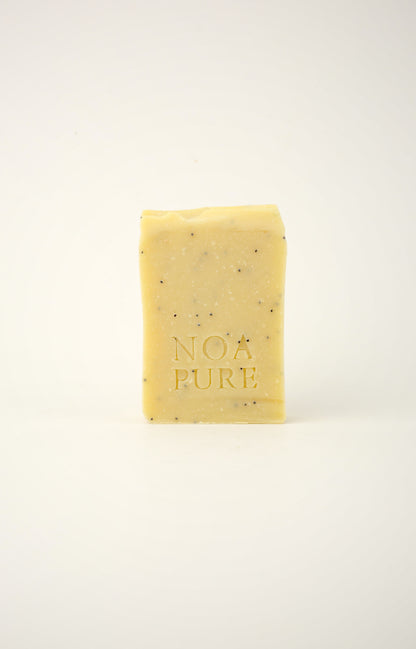 Exfoliating Body Ritual Bar with pale yellow botanical soap and NoaPure embossing on a white background