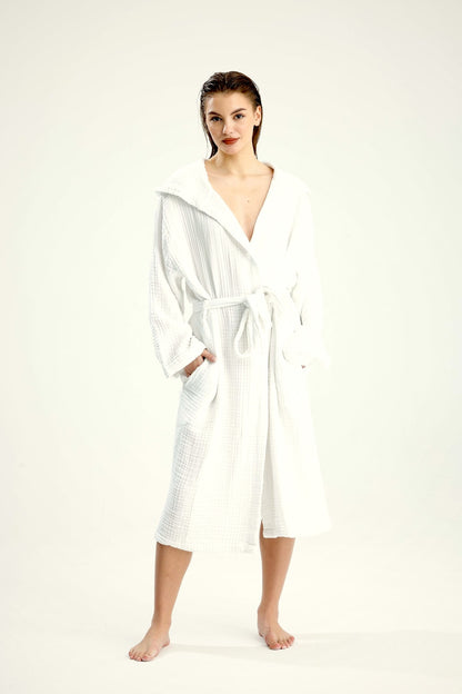 Model wearing a white muslin cotton hooded bathrobe with tie belt, studio view